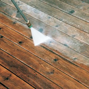 Be careful with the pressure washer. For maximum cleaning with minimal abrasion, the author holds the 15° spray tip 6 in. to 9 in. above the deck and gradually sweeps across the boards in a flattened pendulum motion. 