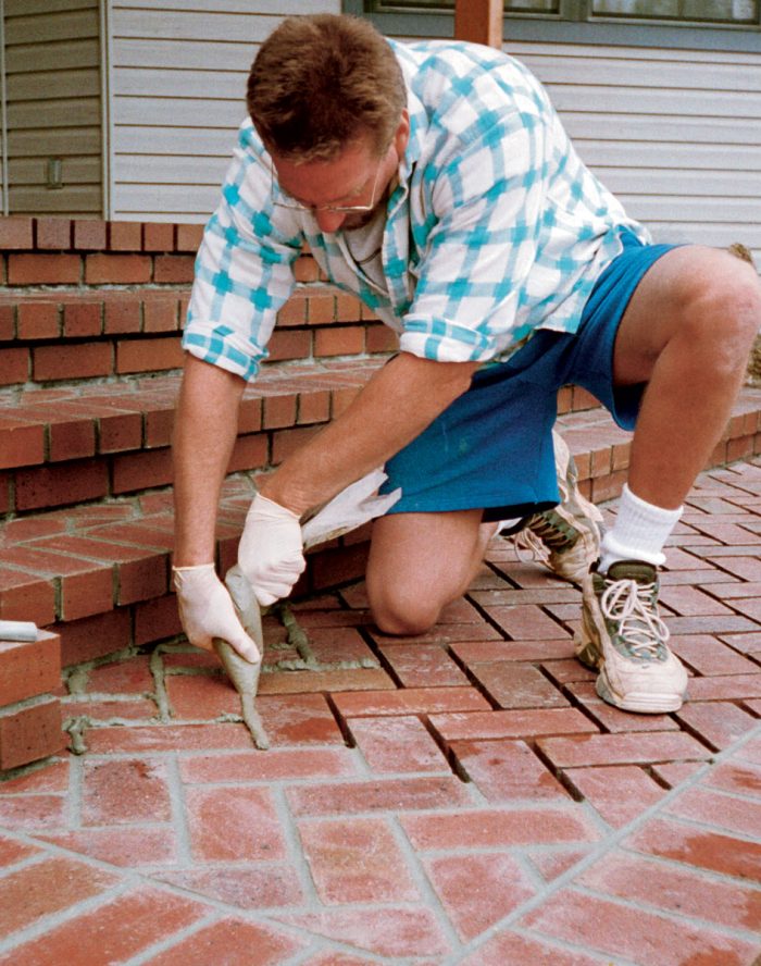Grout, please, with a twist. The joints between bricks are filled with mortar from a grout bag. The bag should be twisted, not rolled, as it dispenses the grout.