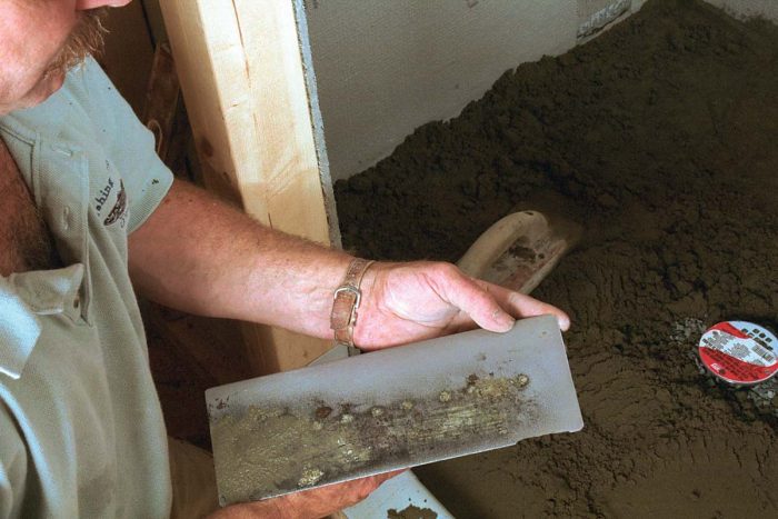 The author rounds the corners of his steel trowel so that there are no sharp corners to puncture the membrane while he’s working the mud layer.