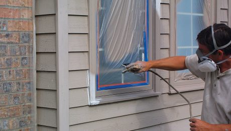 A person spraying paint around a taped window