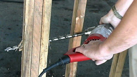 person drilling a hole thru studs