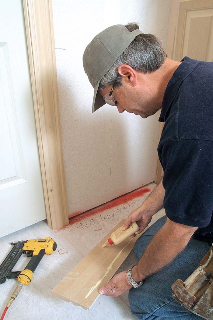 Use 11⁄2-in. finish nails to attach trim pieces because longer nails can extend into the door. Carpenter’s glue backs up the baseboard’s fasteners.