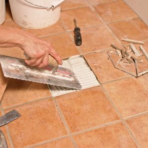 After making sure the replacement tile fits, the author mixes a small batch of thinset, trowels it into the space and sets the tile.