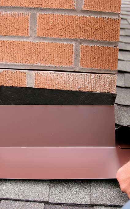 3. Step flashing first. After the peel-and-stick membrane is in place, I shingle and step-flash the roof. This front-apron flashing piece extends over the lower shingles and under the first piece of step flashing.