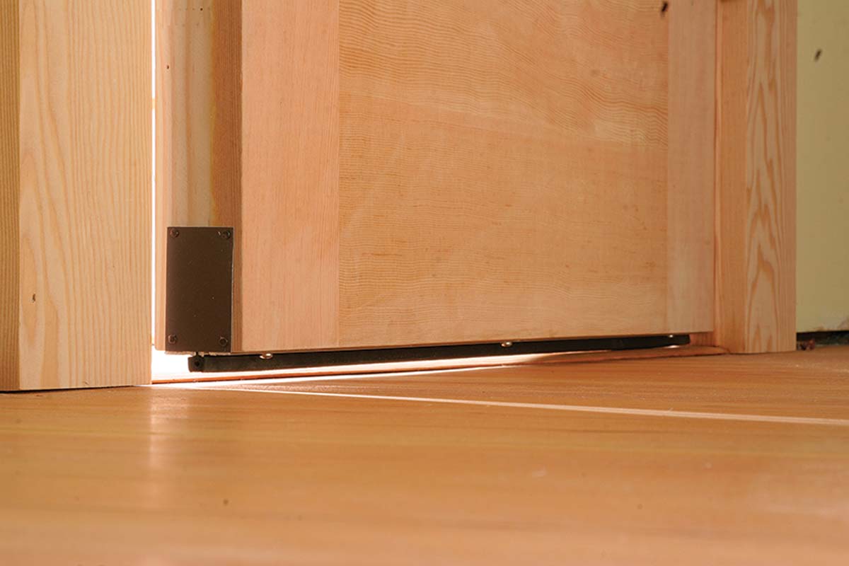 When the door closes, a spring-loaded pin compresses against the hinge-side door jamb to drop the seal.