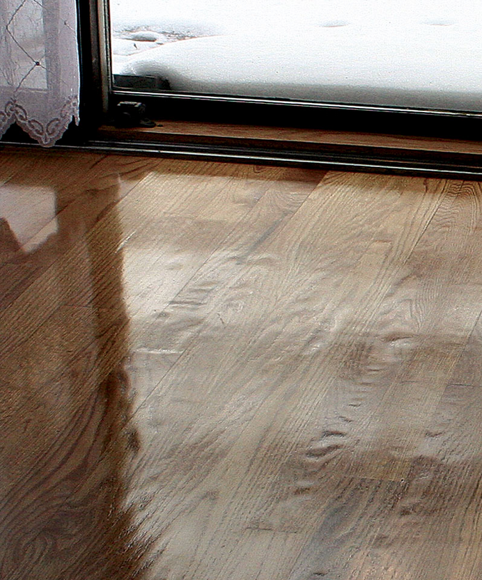The distortion is in the wood, not the finish. Every floorboard contains both soft spring wood, which is the dark grain in each board, and dense late-season wood. The soft spring wood in this floor was dug out by improper sanding.