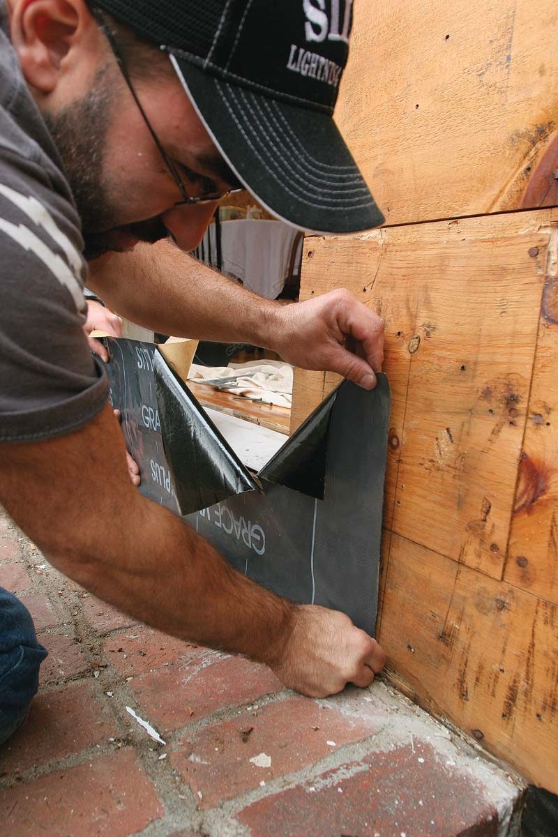 Held to a plumb line on the sheathing, the first piece of flashing extends across the bottom of the opening.