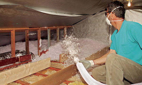 Spraying blown-in fiberglass insulation