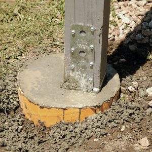 Offset for a reason. With the concrete in place, it’s apparent that the post is not centered. The author offset the footing to make room for an additional post to support a new rim beam.