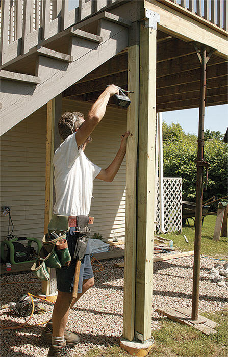 The header needs support. Position 2x4 pressure-treated jacks from the footings to beneath each end of the stringer header, and attach them to the 4x4 posts with structural screws.
