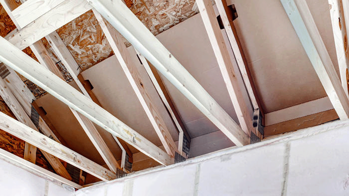 A 14-in. increase in the height of roof trusses leaves more space for insulation at the eaves. A full R-50 of blown-in fiberglass blankets the floor of the vented attic. Netting is stapled to the face of inside studs creating a 9 1/2-in.-deep wall cavity for insulation.