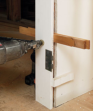 drive a screw through the shim. Small blocks tacked to the drywall register the jamb’s hinge side to the drywall’s face.