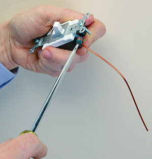 make a loop in a 6-in. length of bare ground wire, fasten it around the green screw terminal, and tighten the screw snugly