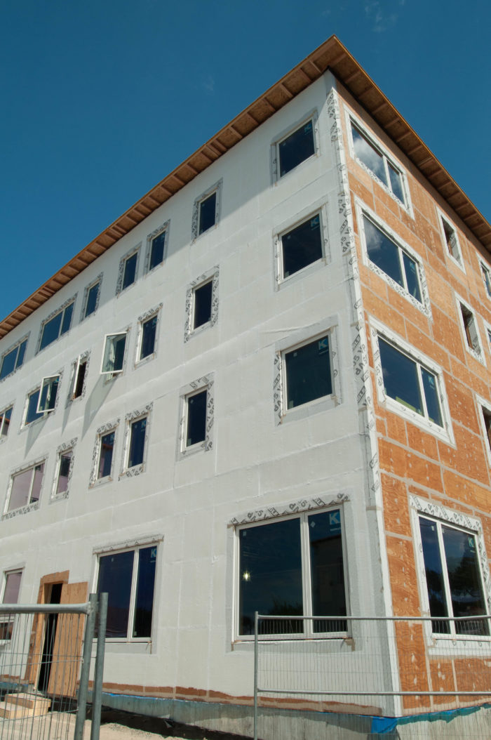 Air-sealing is crucial if the building is to win PHIUS+ 2015 certification. Designers chose a fluid-applied air barrier, seen here as the white coating on the left side of the building. The plywood sheathing on the right has yet to be sealed.