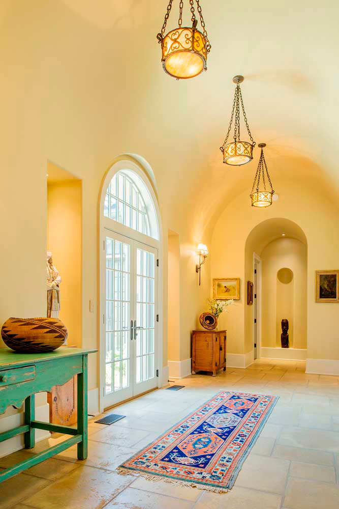French inswing doors crowned by a round top window splash natural light across this arched hallway.