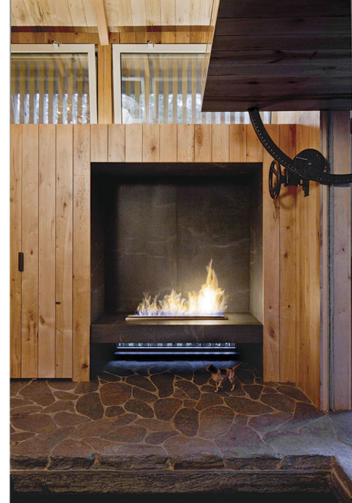 The custom EcoSmart Fire fireplace burns ethanol. The interior walls are reclaimed maple floor planks. The cantilevered door is manually operated by a large wheel and gear.