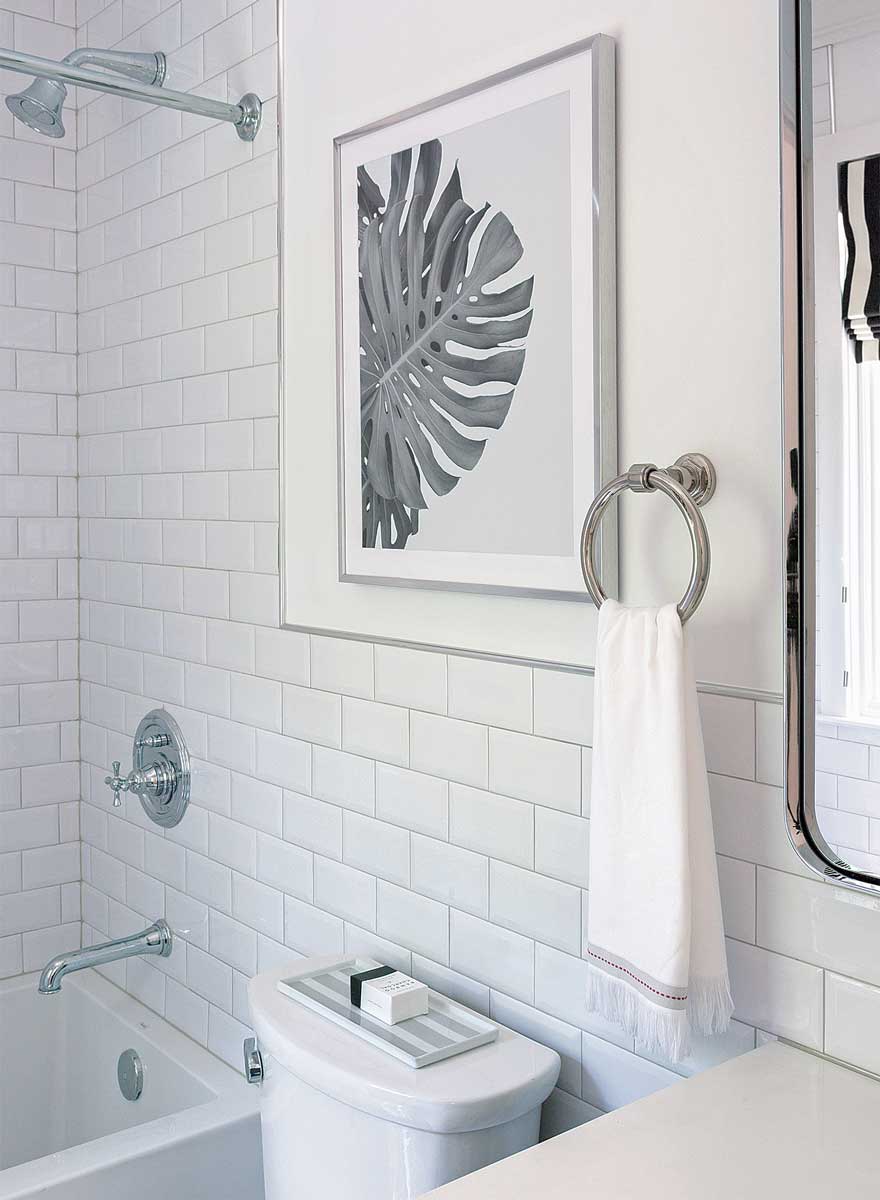 bathroom with white subway tile and leaf picture hanging on the wall