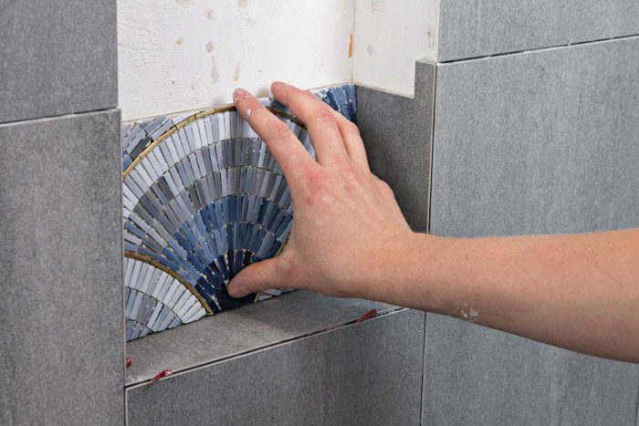 Cut the lower back tiles—in this case a mosaic of glass—to fit with an even gap at either side and along the bottom.