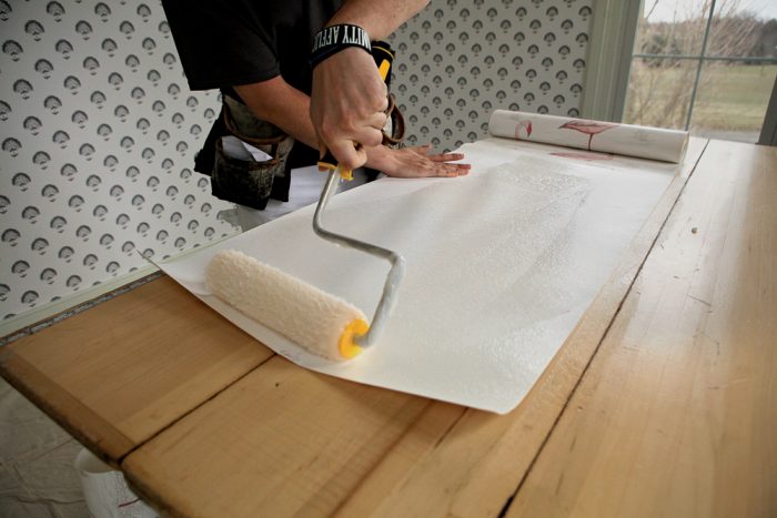 A roller applying paste to the back of wallpaper.