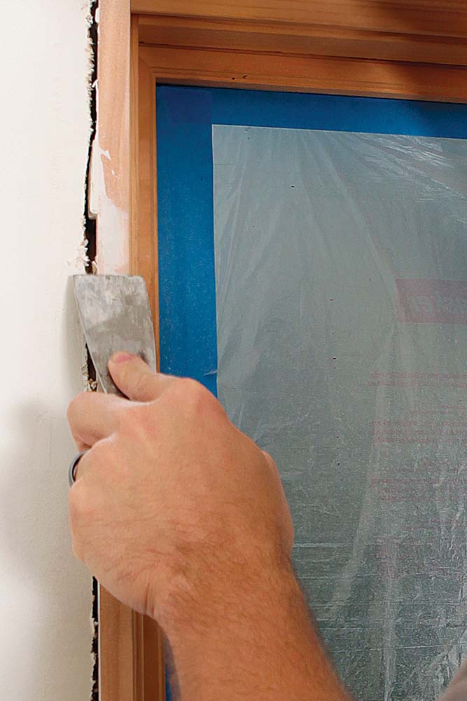 Using a chisel to scrape errant drywall compound