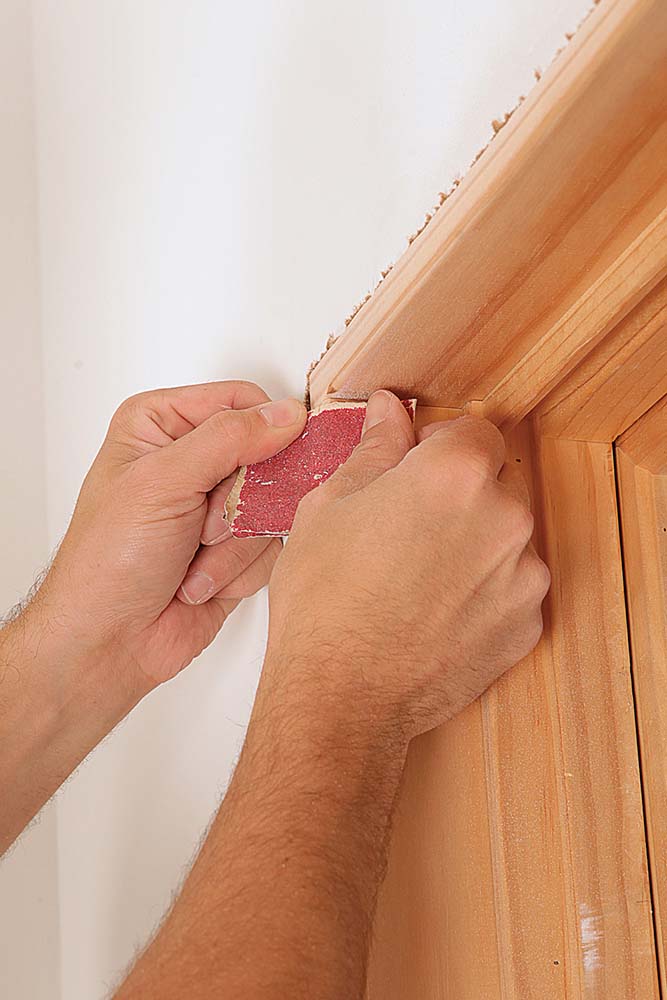 sandpaper being used to finish off the inside corners of the jambs, matching the router bit’s radius; window trim