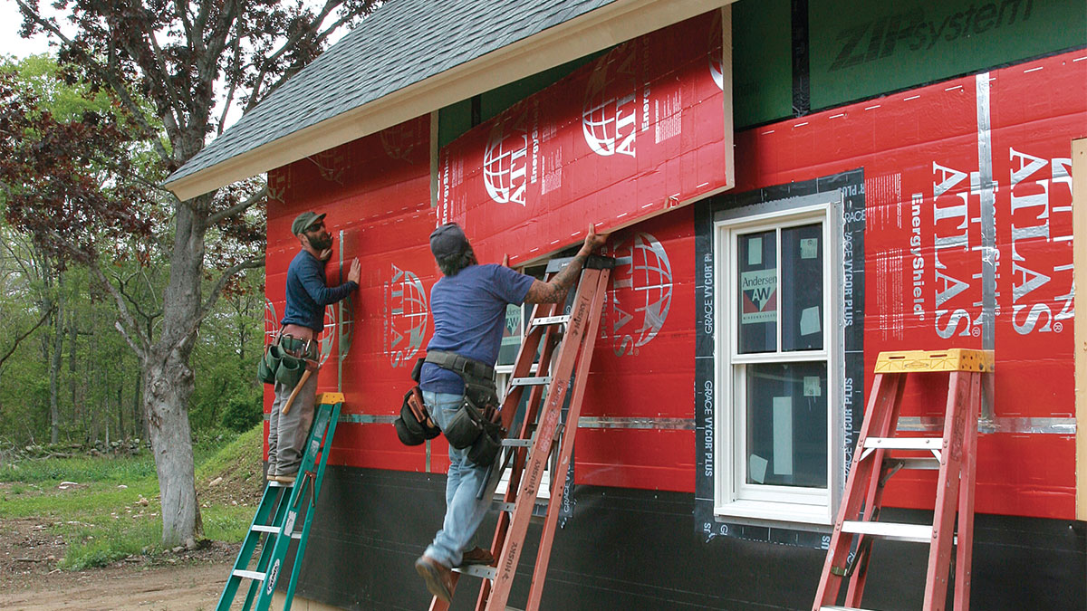 two people working on the exterior of a house 