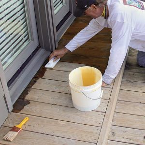 Cut in. Use a brush or painting pad to cut in along the house and anywhere else at risk of overspray from the airless sprayer used for the rest of the deck. I prefer a pad because it holds more finish than a brush.