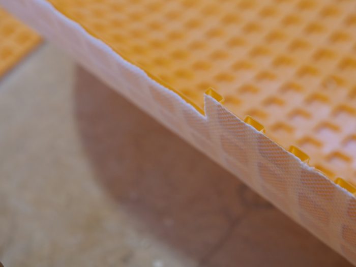 The hollow plastic grid on the upper surface of the Ditra allows the tile to move horizontally