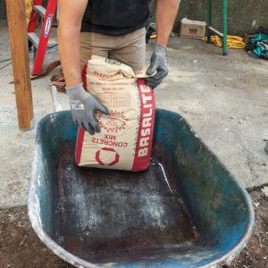 bag of concrete in wheelbarrow; mixing concrete by hand