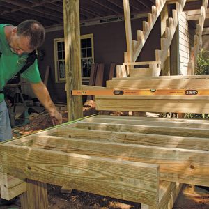 Build the landing in place. With a pair of carrying beams in place, the landing box can be framed. Note the clipped corner detail and 12-in.-on-center framing. Like the deck above, the landings are decked with a diagonal pattern. 