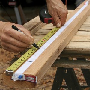 Mark the template. With one end pinned, stretch the elastic about 1 ft. longer than the longest rail. Relax it about 10 in., and pin the other end. Snap it a couple of times to equalize the stretch, then mark the ends of the longest rail and the baluster spacing.