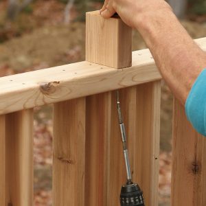 Screw the center blocks. To maintain the 4-in. spacing between the cap rail and the railing section below, fasten 2x4 blocks with 2-1⁄2-in. stainless-steel screws. Like the posts, the tops pitch 3° for drainage.
