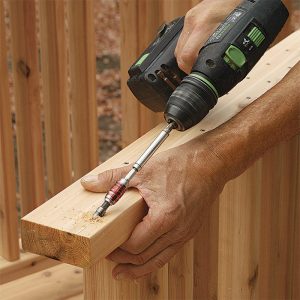 Drill the rails for toe-screws. The rails are screwed to the 4x4 posts from the bottom to hide the 2-1⁄2-in. stainless-steel screws. Drill the pilot holes at about a 60° angle through the bottom ends of the rails.