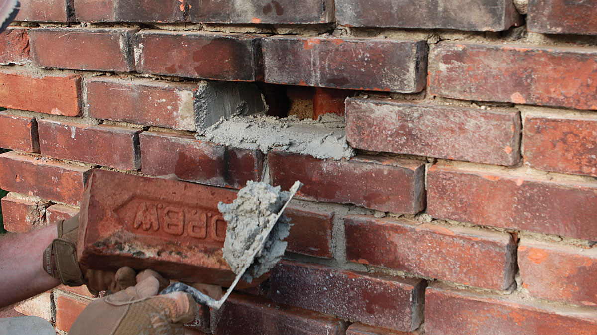 Butter the brick. Fill manufacturer stamps with mortar to prevent voids and ensure a good bond between the brick and mortar.