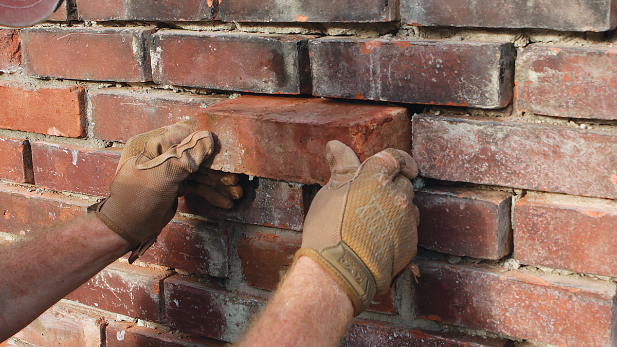Push it in. Carefully insert the brick into the hole, keeping it centered side-to-side, then wiggle it down into the bed mortar.