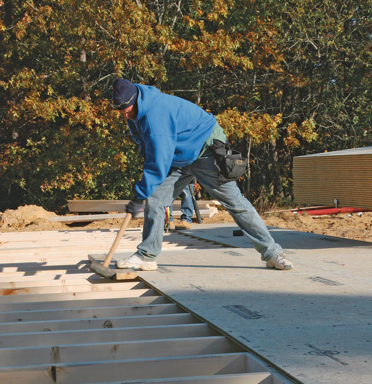 To mate the tongue and groove edges, have a helper stand on the edges as you drive the sheet into place. When working solo, hold the edges in line with one foot as you tap with the sledge hammer.