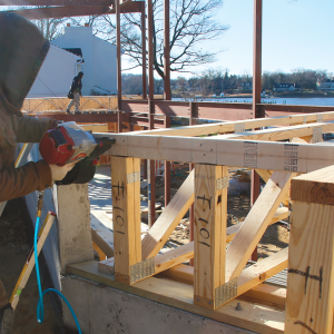 Connect the top chords. These trusses, which are flush with the foundation wall, have a 2x4 band to help plumb the trusses and strengthen the assembly. We transfer the truss layout to the band before installing it, and follow the component manufacturer’s instructions for fastening.