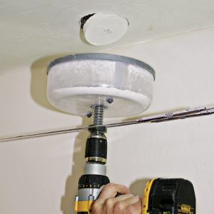 4  Hold the cover snug against the ceiling as you drill.