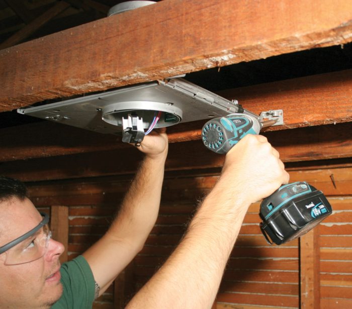 Man attaching hangers of a ceiling box to joists.