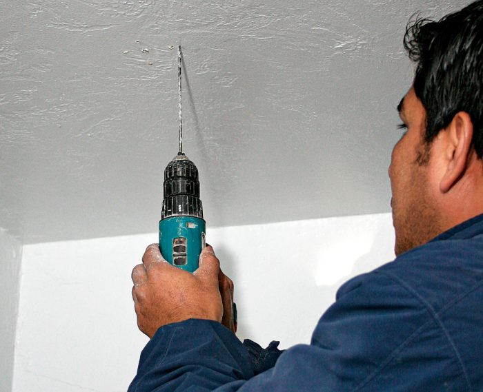 To run cable to a ceiling fixture, start by drilling an exploratory hole with a small-diameter bit.