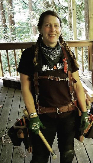 Woman Carrie Healy stands on deck with her tool bag and a hammer