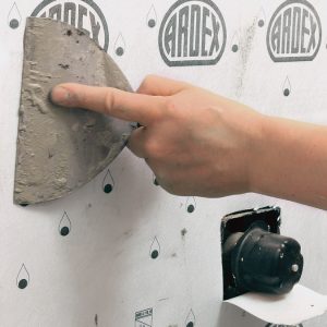 Collapse the ridges. Use a flat trowel to evacuate all of the air bubbles and flatten the thinset ridges to get adhesion across 100% of the surface. Run your hands over it last to feel for any lingering air pockets, and push those to the edge with the trowel.