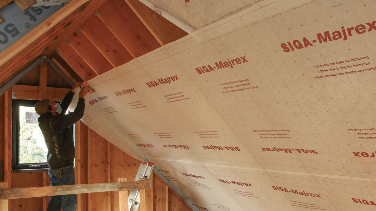 Vapor-permeable air barrier. The Siga Majrex is rolled out and cut on the floor, and then lifted up and installed perpendicular to the rafters. 