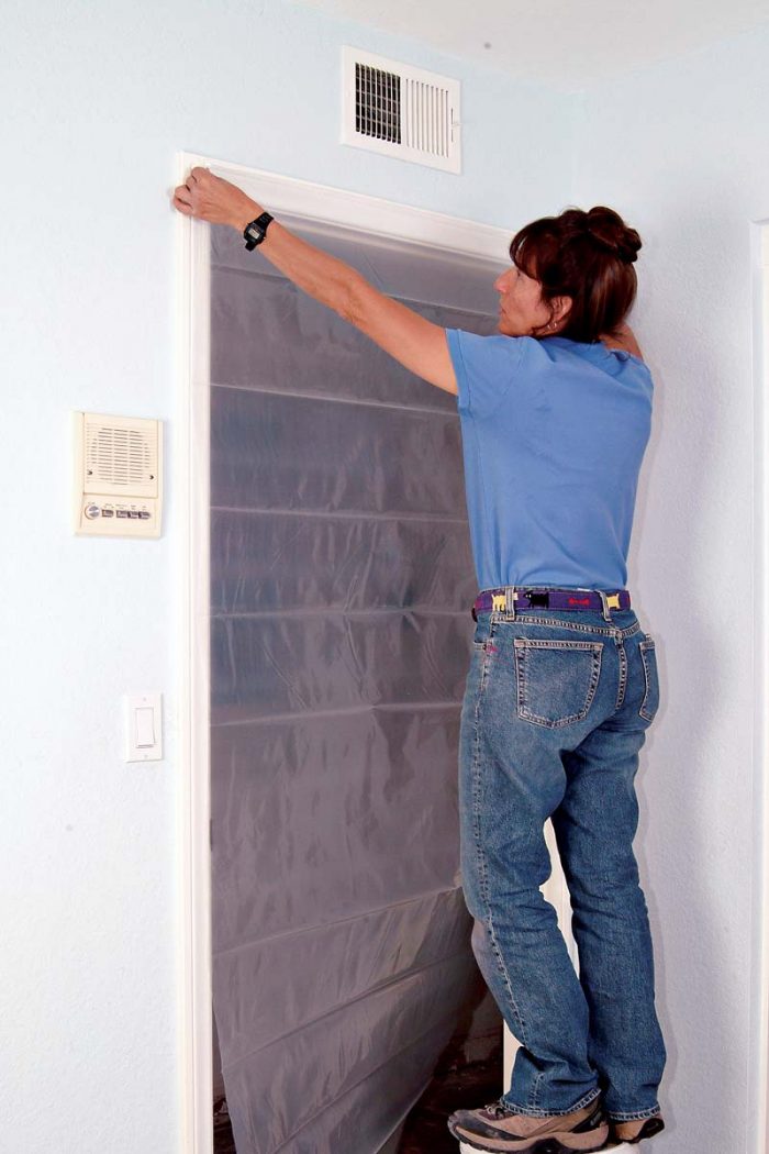 Taping plastic sheeting over a doorway keeps out dust
