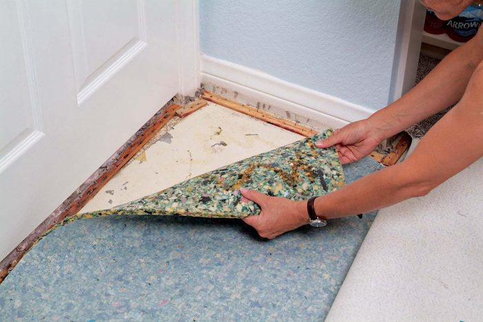 Peel the carpet padding back from the floor, being careful to watch for staples.
