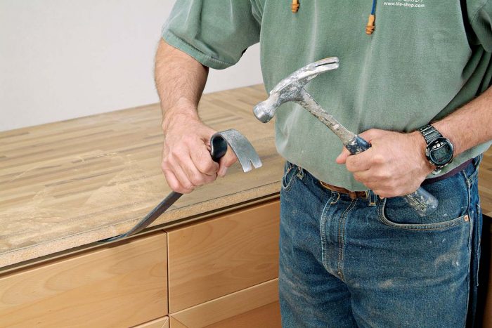 Insert a prybar under the countertop and lift it from the cabinet frames.