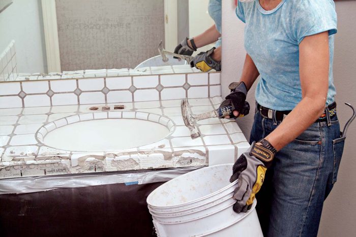 Hammer off the edge trim tiles into a bucket to start your countertop demolition.