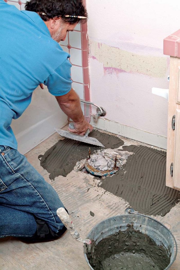 Use the short end of a trowel to spread thinset in cramped areas, such as around this toilet flange.