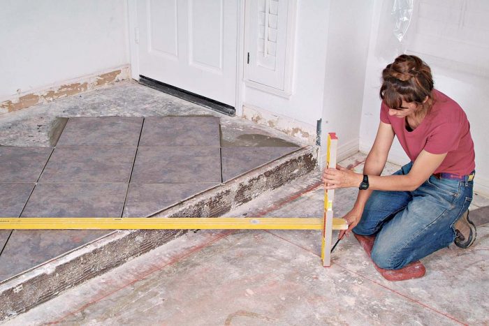 A long and a short level are used to transfer the layout lines from the entry area to the living/dining room floor.