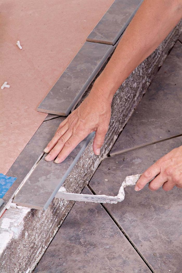 Use a margin trowel to remove excess thinset from the overhanging edge of the trim tiles.